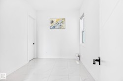 Bright room featuring large format tile flooring, white walls, and a single window - 