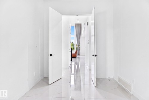 White walls and large format tile flooring complement contemporary doors with matte black hardware - 3926 41 Avenue, Beaumont, AB - Indoor Photo Showing Other Room