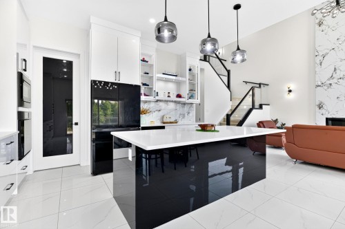 Open-concept kitchen featuring a large central island with a white countertop and dark, reflective base - 3926 41 Avenue, Beaumont, AB - Indoor