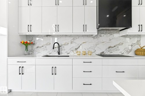 Modern kitchen featuring white high-gloss cabinetry with black hardware, a black kitchen faucet, and a black range hood - 3926 41 Avenue, Beaumont, AB - Indoor Photo Showing Kitchen