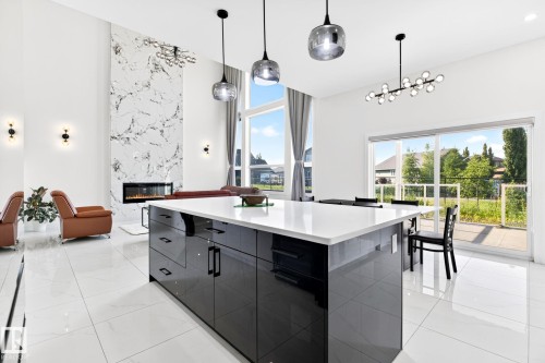 Contemporary kitchen island with a white countertop and high-gloss black cabinetry - 3926 41 Avenue, Beaumont, AB - Indoor Photo Showing Kitchen