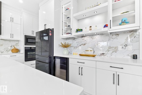 Sleek kitchen featuring white cabinetry, a large white countertop surface, and a marble-patterned backsplash - 3926 41 Avenue, Beaumont, AB - Indoor Photo Showing Kitchen