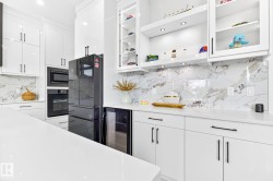 Sleek kitchen featuring white cabinetry, a large white countertop surface, and a marble-patterned backsplash - 