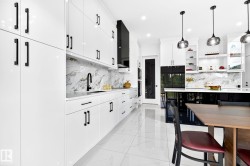 Modern kitchen featuring high-gloss white cabinetry with matte black hardware, a marble-patterned backsplash, and polished white floor tiles - 
