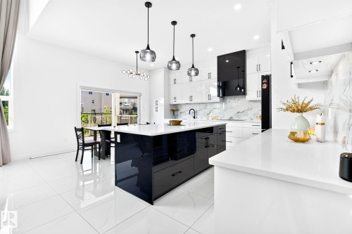 Modern kitchen featuring a large central island with a high-gloss black finish and white countertop - 3926 41 Avenue, Beaumont, AB - Indoor Photo Showing Kitchen With Upgraded Kitchen