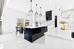 Modern kitchen featuring a large central island with a high-gloss black finish and white countertop - 