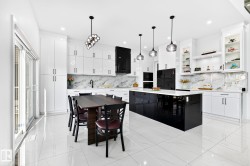 Contemporary kitchen featuring a large black center island with a white countertop - 
