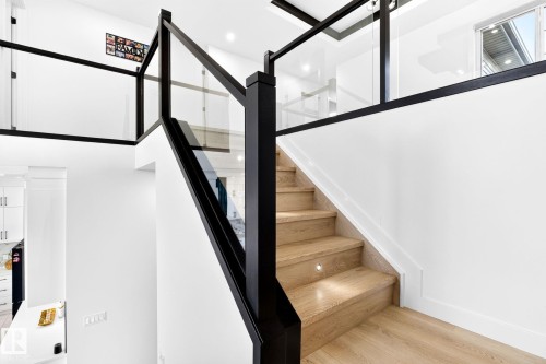 Modern staircase featuring light wood-finish treads with integrated step lighting and black newel posts - 3926 41 Avenue, Beaumont, AB - Indoor Photo Showing Other Room