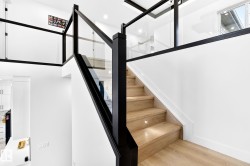 Modern staircase featuring light wood-finish treads with integrated step lighting and black newel posts - 