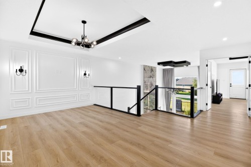 Open concept living area featuring wood-finish flooring, decorative wall paneling, and a contemporary chandelier - 3926 41 Avenue, Beaumont, AB - Indoor Photo Showing Other Room
