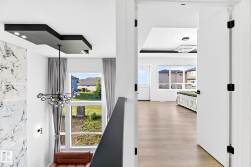 Modern chandelier and marble-patterned wall paneling complement the contemporary ceiling design with recessed lighting - 3926 41 Avenue, Beaumont, AB - Indoor Photo Showing Other Room