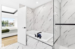 Bathroom featuring a built-in soaking tub with matte black fixtures, marble-patterned tile flooring and wall surround, and a glass shower enclosure with a black frame - 
