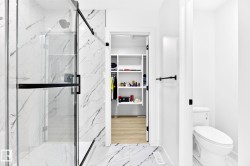 Contemporary bathroom featuring a spacious glass-enclosed shower with black fixtures and marble-finish tile, coordinated marble-finish flooring, and a separate water closet - 