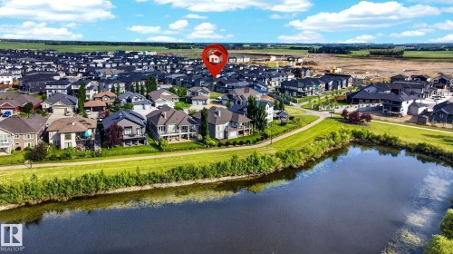 Aerial perspective showcasing a residential development with a prominent pond and green space - 3926 41 Avenue, Beaumont, AB - Outdoor With Body Of Water With View