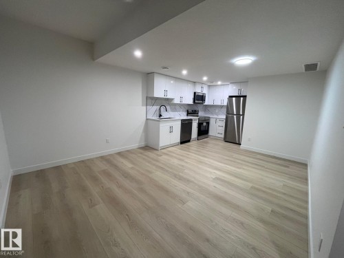 Open-concept living space with light wood-finish flooring, recessed lighting, and a modern kitchen - 3926 41 Avenue, Beaumont, AB - Indoor