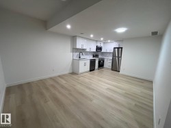 Open-concept living space with light wood-finish flooring, recessed lighting, and a modern kitchen - 