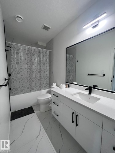 Modern bathroom featuring a single white vanity with a rectangular integrated sink, black faucet, and black hardware - 3926 41 Avenue, Beaumont, AB - Indoor Photo Showing Bathroom