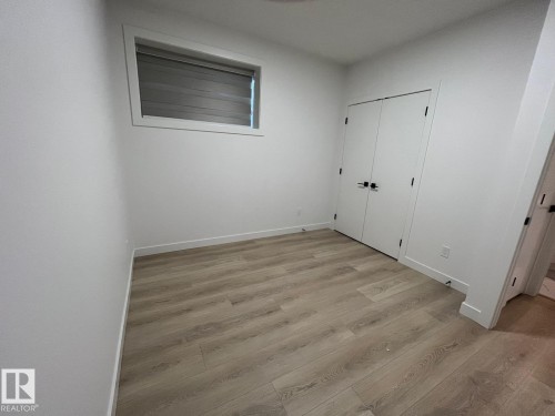 Light wood-finish flooring complements white walls - 3926 41 Avenue, Beaumont, AB - Indoor Photo Showing Other Room