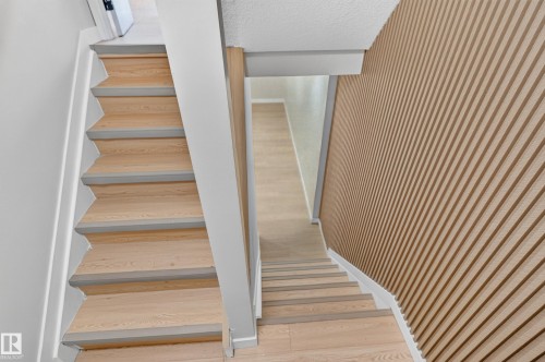 Elegant staircase featuring wood-finish treads with white painted risers and modern white railings - 175 Centennial Crest Nw, Edmonton, AB - Indoor Photo Showing Other Room