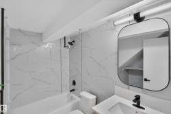 Bathtub with black hardware and marble-patterned wall surfacing - 