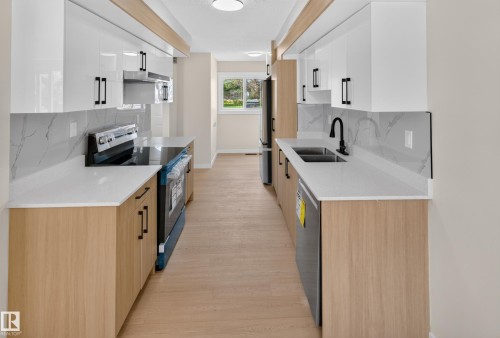 Galley kitchen featuring light wood-finish lower cabinetry, white upper cabinetry, and white countertops - 175 Centennial Crest Nw, Edmonton, AB - Indoor Photo Showing Kitchen With Double Sink With Upgraded Kitchen