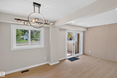 Wood-finish flooring, contemporary chandelier, sliding glass door, white trim window, and textured accent wall - 175 Centennial Crest Nw, Edmonton, AB - Indoor Photo Showing Other Room