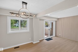 Wood-finish flooring, contemporary chandelier, sliding glass door, white trim window, and textured accent wall - 