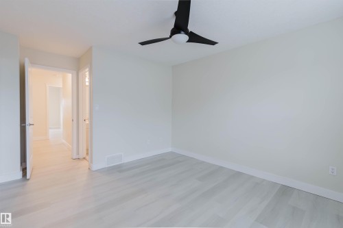 Wood-finish flooring, white walls, and a contemporary black ceiling fan - #2 13215 153 Av Nw, Edmonton, AB - Indoor Photo Showing Other Room