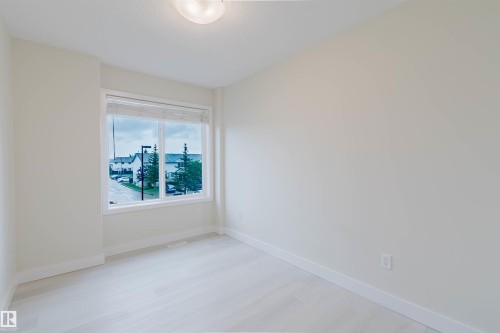 Light-toned wood-finish flooring, neutral wall tones, large window, and overhead lighting fixture - #2 13215 153 Av Nw, Edmonton, AB - Indoor Photo Showing Other Room