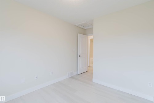 Light-toned wall finishes, light wood-finish flooring, white trim, and a paneled interior door - #2 13215 153 Av Nw, Edmonton, AB - Indoor Photo Showing Other Room
