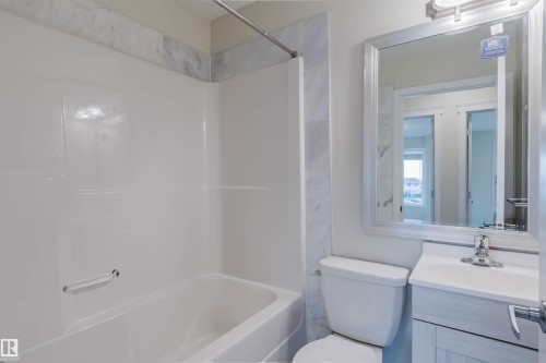 Bathroom featuring a white bathtub, white vanity with integrated sink, and an overhead light fixture - #2 13215 153 Av Nw, Edmonton, AB - Indoor Photo Showing Bathroom