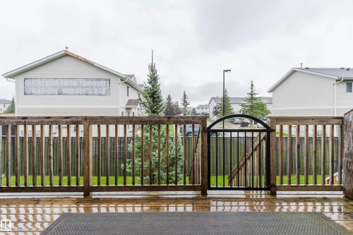 Wood deck flooring with a black metal gate and wood railing - #2 13215 153 Av Nw, Edmonton, AB - Outdoor With Deck Patio Veranda With Exterior