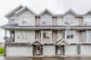 Multi-unit structure with varied siding, multiple window styles, integrated garage doors, and stone-finish accents - #2 13215 153 Av Nw, Edmonton, AB  - Outdoor With Facade 