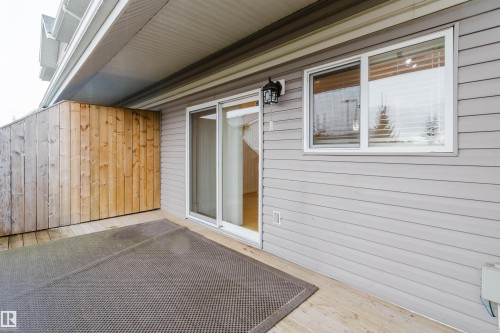 Private patio with a wood privacy fence, light gray siding, and a sliding glass door - #2 13215 153 Av Nw, Edmonton, AB - Outdoor With Deck Patio Veranda With Exterior