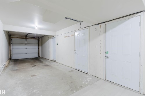 Attached garage with concrete flooring, recessed lighting, and white paneled doors - #2 13215 153 Av Nw, Edmonton, AB - Indoor Photo Showing Garage