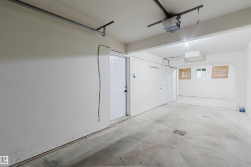 Spacious garage with concrete flooring, overhead lighting, and multiple access doors - #2 13215 153 Av Nw, Edmonton, AB - Indoor Photo Showing Garage
