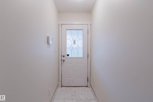 Entryway featuring a white door with decorative glass inserts, white trim, and light-toned tile flooring - #2 13215 153 Av Nw, Edmonton, AB - Indoor Photo Showing Other Room