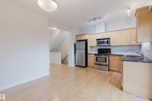 Light wood-finish flooring throughout - #2 13215 153 Av Nw, Edmonton, AB - Indoor Photo Showing Kitchen With Stainless Steel Kitchen With Double Sink