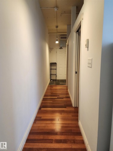 Wood-finish flooring leading to an entryway with dark tile - #1002 10024 Jasper Av Nw, Edmonton, AB 