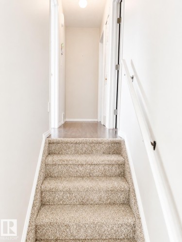Carpeted staircase with a white handrail, leading to a hallway with wood-finish flooring - 802 16 Avenue, Cold Lake, AB - Indoor Photo Showing Other Room
