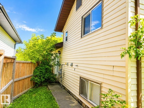 Siding exterior with multiple windows, concrete pathway, and wood privacy fencing - 802 16 Avenue, Cold Lake, AB - Outdoor With Exterior