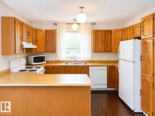 Kitchen featuring wood-finish cabinetry, wood-finish countertops, and wood-finish flooring - 802 16 Avenue, Cold Lake, AB - Indoor Photo Showing Kitchen With Double Sink