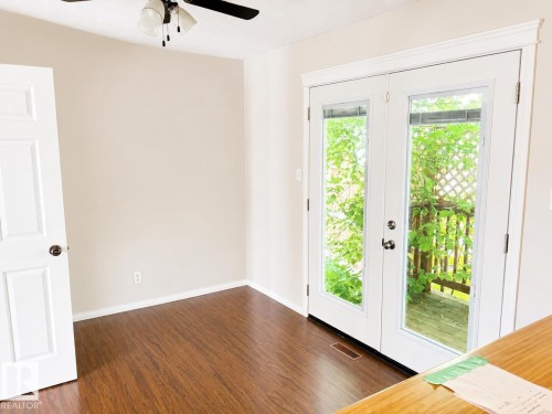 Wood-finish flooring, ceiling fan, white paneled door, double French doors, and outdoor wooden decking - 802 16 Avenue, Cold Lake, AB - Indoor Photo Showing Other Room