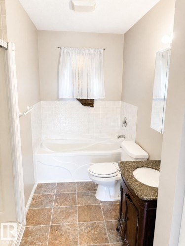 Bathroom featuring a built-in tub with tile surround, a dark wood-finish vanity with a granite-style countertop, and square floor tiling - 802 16 Avenue, Cold Lake, AB - Indoor Photo Showing Bathroom