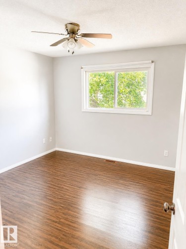 Wood-finish flooring, white trim, recessed window with white framing, and a ceiling fan with integrated lighting - 802 16 Avenue, Cold Lake, AB - Indoor Photo Showing Other Room