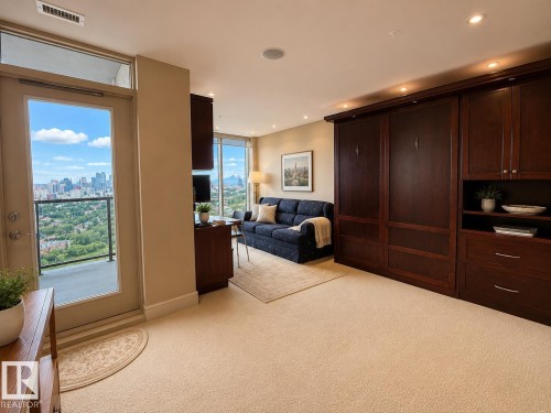 Expansive windows and glass door leading to a balcony, light-toned carpeting, dark wood-finish built-in cabinetry, recessed ceiling lighting, and a cityscape backdrop - #1201 10035 Saskatchewan Dr Nw, Edmonton, AB - Indoor