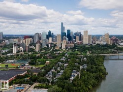 Expansive urban landscape featuring a prominent cityscape, a tree-lined river, a bridge structure, and residential areas - 