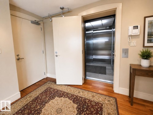 Hardwood flooring, track lighting, stainless steel elevator, intercom system, and a solid core door - #1201 10035 Saskatchewan Dr Nw, Edmonton, AB - Indoor Photo Showing Other Room