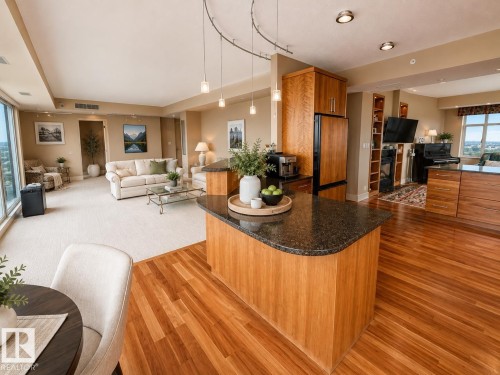 Open-concept living space featuring wood-finish flooring, a kitchen island with stone countertop, wood-finish cabinetry, and recessed lighting - #1201 10035 Saskatchewan Dr Nw, Edmonton, AB - Indoor Photo Showing Living Room