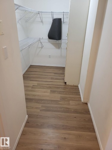 Walk-in closet featuring wood-finish flooring, white wire shelving, and white baseboards - #202 8802 Southfort Dr, Fort Saskatchewan, AB - Indoor